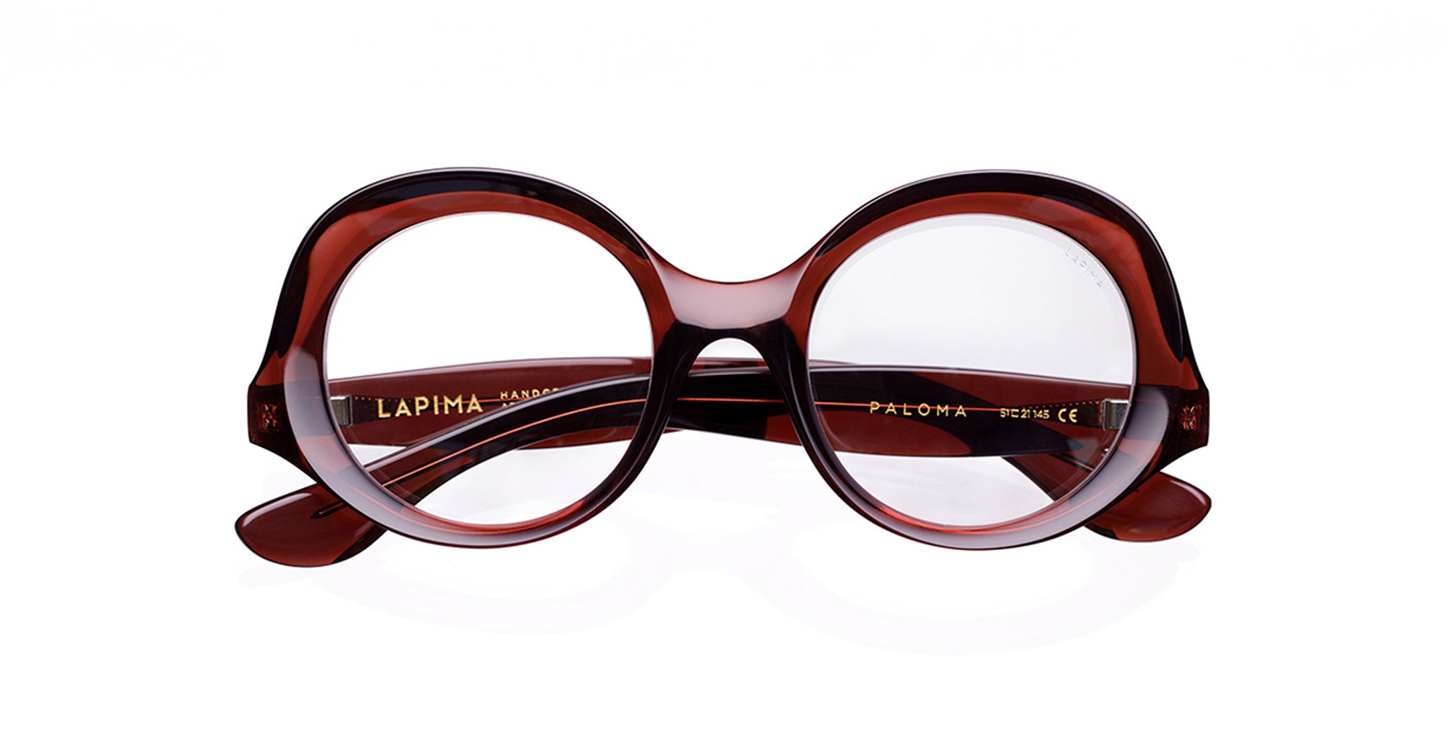 The Lapima Paloma features oversized round eyeglasses with a thick dark red and brown tortoiseshell Italian acetate frame, handcrafted in Brazil. Shown on a white background, the inside arm displays the text "Lapima Paloma.