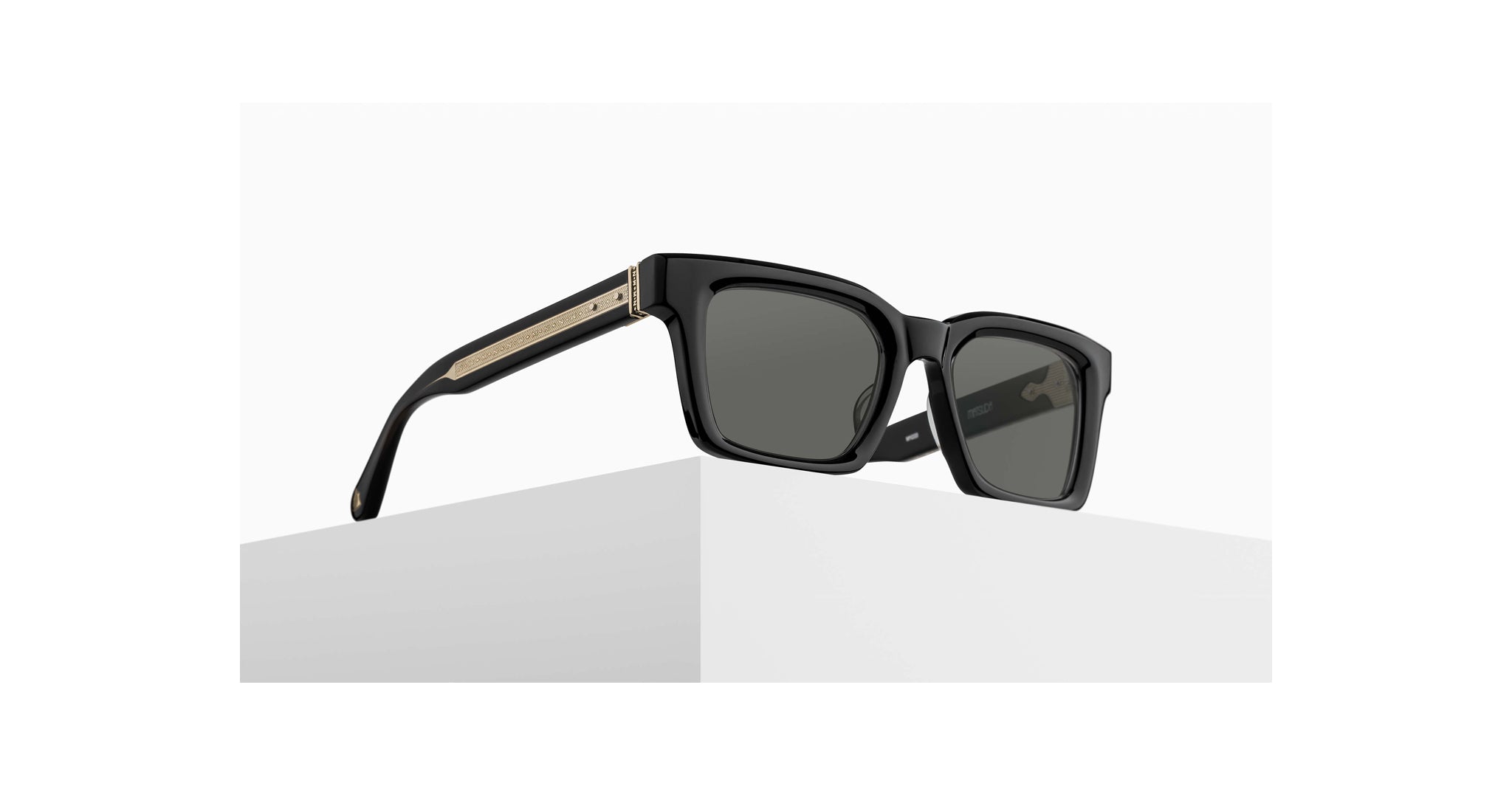The Matsuda M1033 features sleek black rectangular frames, dark lenses, and gold-accented arms, shown resting on a white geometric surface against a plain background.