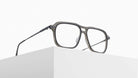 The Matsuda M2062, a pair of stylish eyeglasses with rectangular frames, rests on the edge of a white minimalist block against a plain white background.