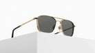 The Matsuda M3135 gold-framed aviator sunglasses with dark lenses rest on a white geometric surface against a plain, light background.