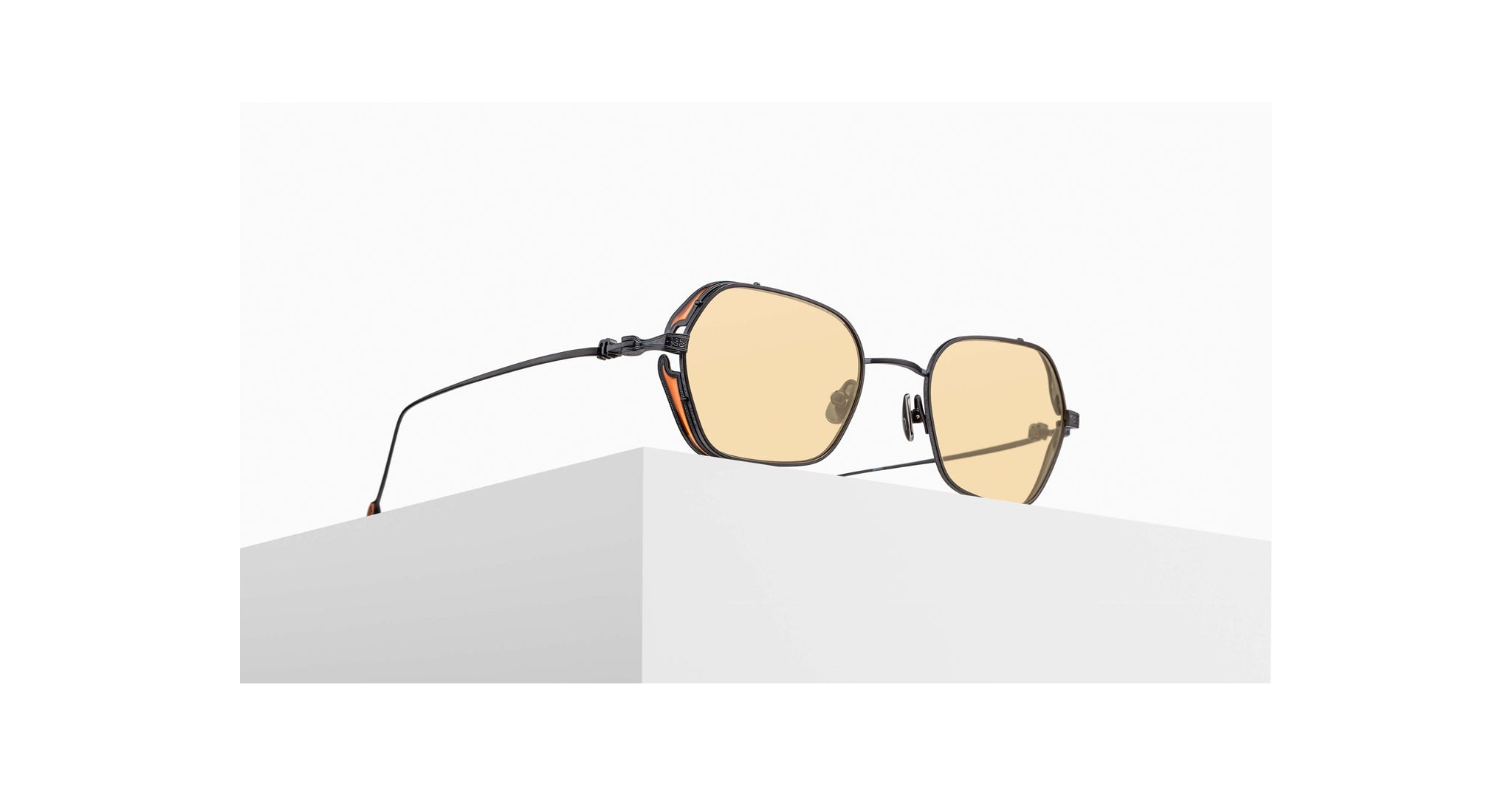 3/4 view of the Matsuda model M3153 sunglass in color Matte Black with orange lenses sitting on a pedestal