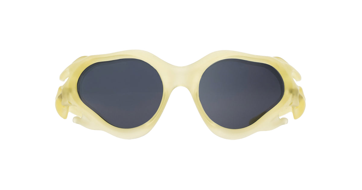 Paloceras Hydroceras sculpted organic oval sunglasses in Oneryth, with a translucent pale yellow frame and dark gray lenses, front view.
