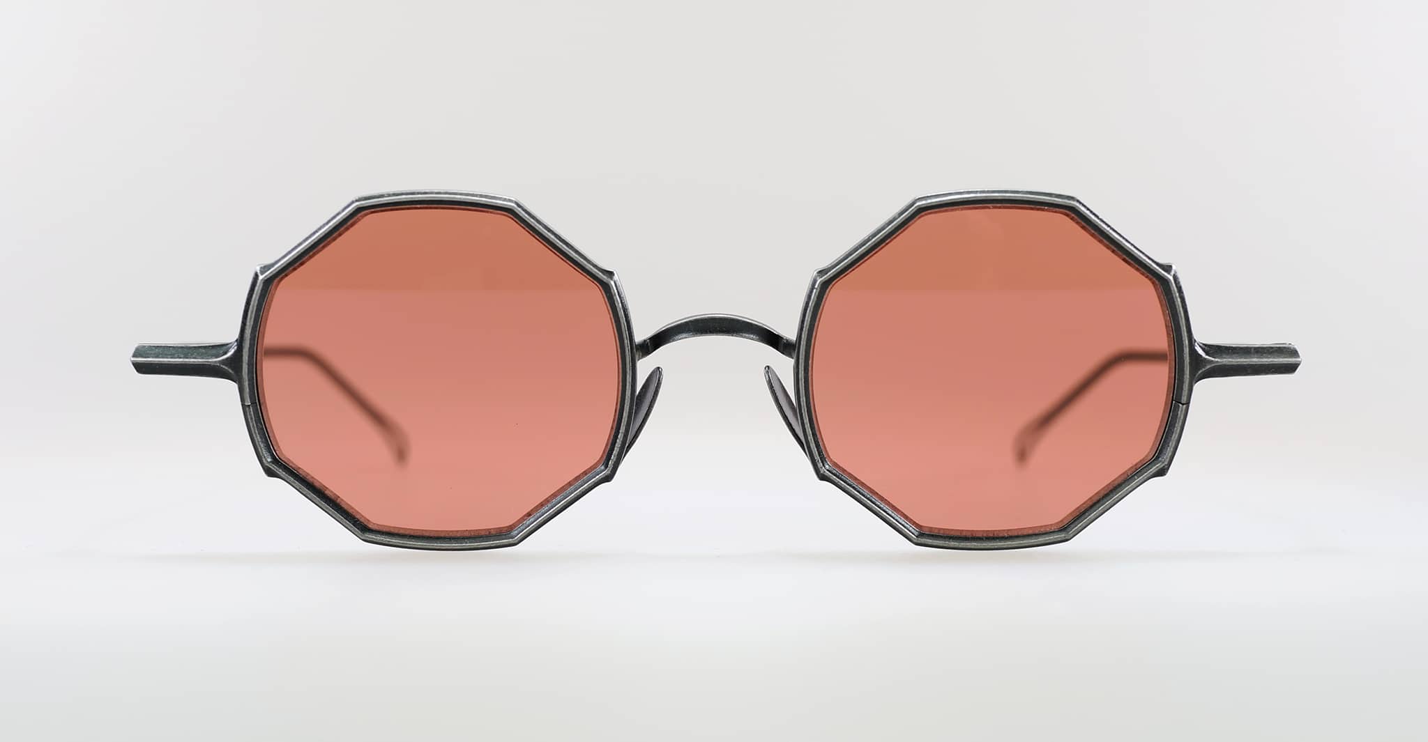 A pair of round eyeglasses with octagonal frames and pink-tinted lenses, displayed against a plain white background.