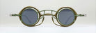 Round sunglasses with olive green metal frames, dark lenses, and a unique double bridge design with angular geometric details, displayed against a plain light background.