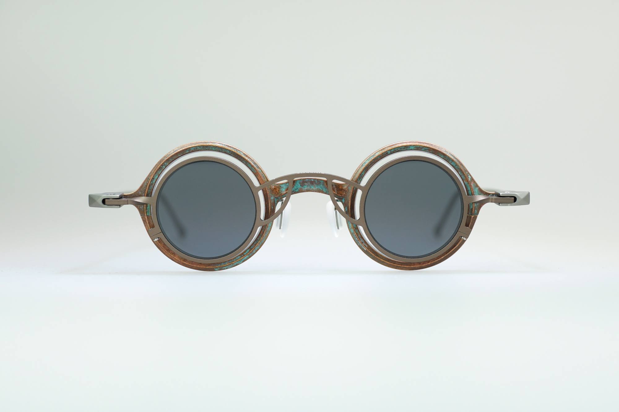 Round sunglasses with dark lenses and a thick, textured, multicolored frame featuring earth tones, shown against a plain light background.