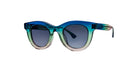 Thierry Lasry Consistency: Round sunglasses featuring blue, green, and beige gradient frames with dark tinted lenses, shown on a white background.