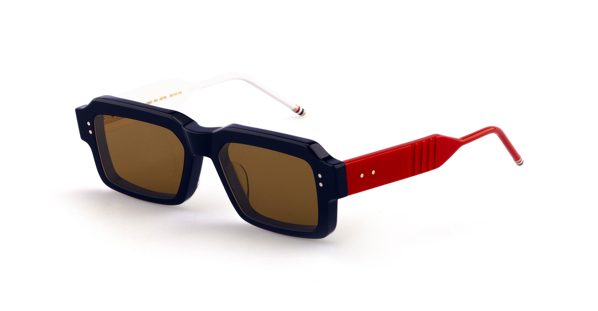 A pair of rectangular-shaped Thom Browne sunglasses with thick black frames, brown lenses, white left temple arm, and red right temple arm, both with thin curved ends.