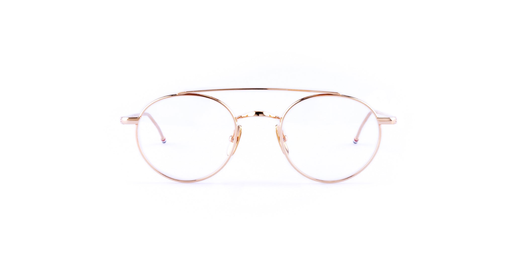 A pair of round, gold metal eyeglasses—Thom Browne 101 in Rose Gold—with clear lenses is shown against a plain white background.