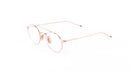 A pair of round, thin metal eyeglasses with rose gold frames and clear lenses rests on a white background. The temples have subtle colored tips, showcasing the refined style of Thom Browne 101 eyeglasses in Rose Gold.
