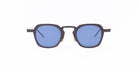 A pair of Thom Browne sunglasses with thick, black geometric frames and blue-tinted square lenses.