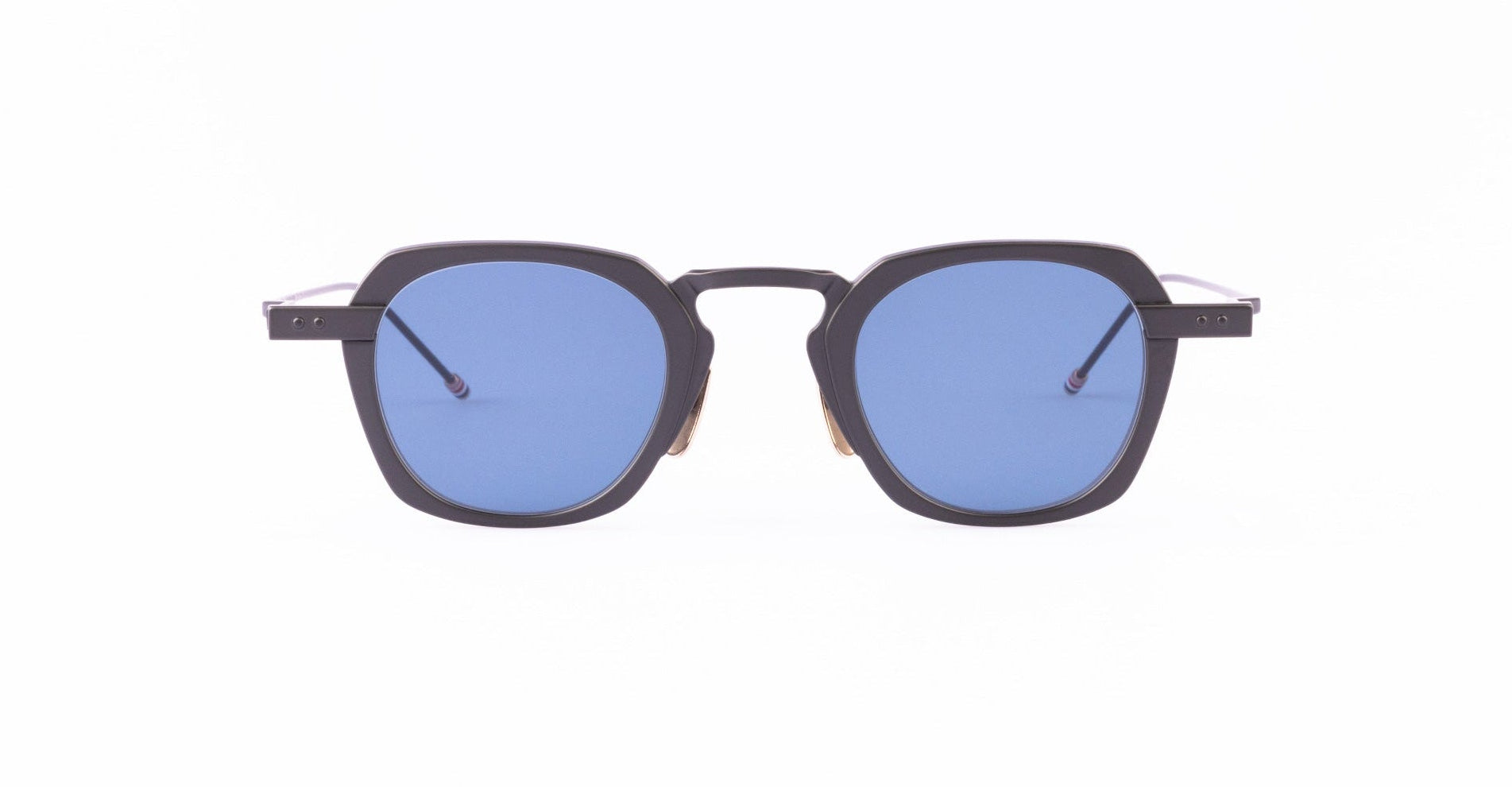A pair of Thom Browne sunglasses with thick, black geometric frames and blue-tinted square lenses.