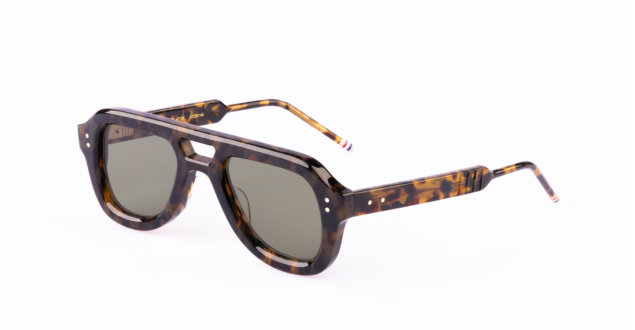 A pair of Thom Browne sunglasses with a thick, dark tortoiseshell frame and green tinted lenses. The temples have a striped detail near the tips.