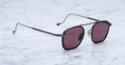 Jacques Marie Mage Baudelaire sunglasses with black frames and dark red lenses, front view.