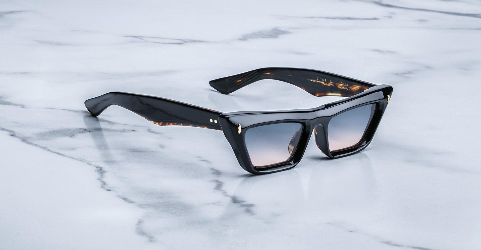 Jacques Marie Mage Debbie in Noir acetate cat-eye frame with gradient gray lenses, featuring gold arrowhead pins and sculpted temples with exposed wirecore