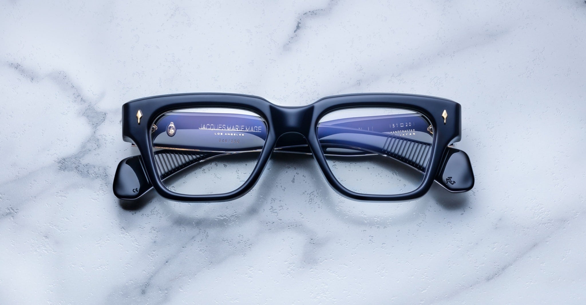 Jacques Marie Mage Fellini black rectangular eyeglasses with gold accents, front angle view.
