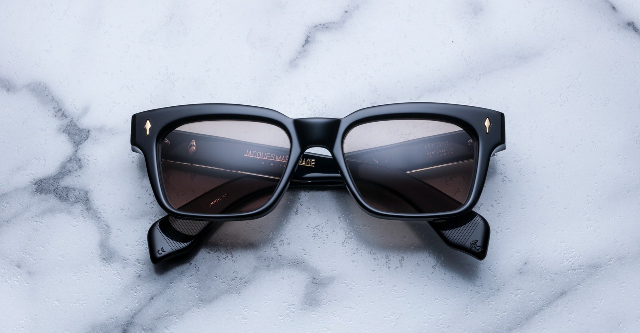 Jacques Marie Mage Molino black rectangular sunglasses with polarized lenses, top-down view.