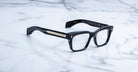 Jacques Marie Mage Molino black rectangular eyeglasses, thick frames, gold-accented arms, shown from above angle.