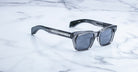 Jacques Marie Mage Molino sunglasses with gray frames and dark lenses, viewed from above.