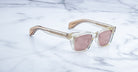 Jacques Marie Mage Molino square sunglasses with gold and clear arms, light pink lenses, front view.