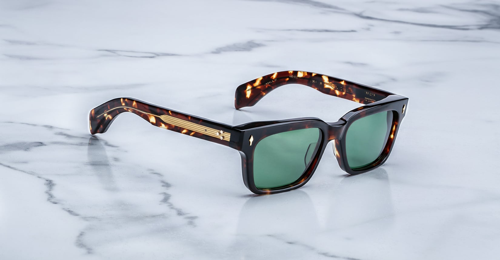 Jacques Marie Mage Molino 55 sunglasses featuring green lenses and gold accents, shown from above.