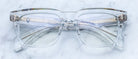 Handcrafted clear acetate Jacques Marie Mage Torino eyeglasses with bold rectangular frames and silver hinges by Jacques Marie Mage, shown on a light marble surface.