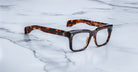 The Jacques Marie Mage Torino features bold, handcrafted rectangular acetate frames by Jacques Marie Mage, displayed on a white marble surface.