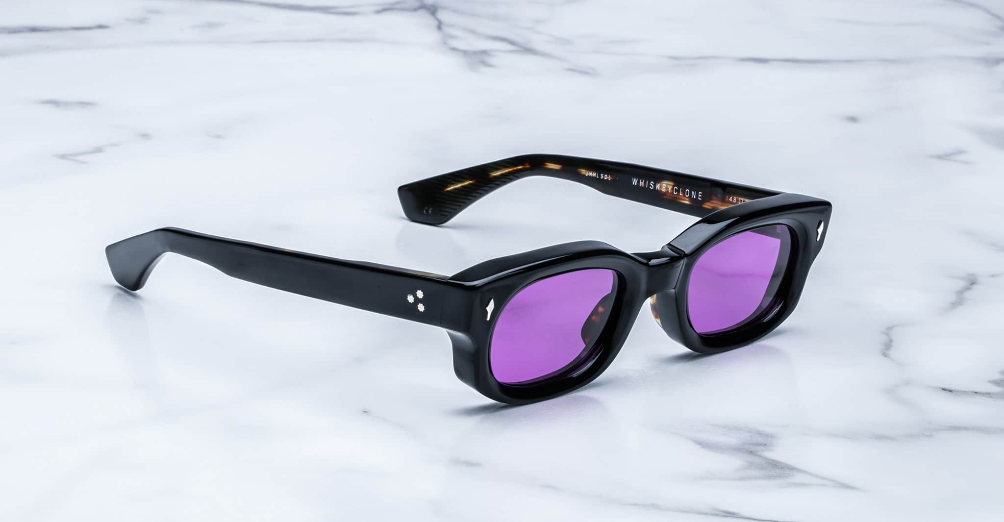 Jacques Marie Mage Whiskeyclone sunglasses with thick frames and purple lenses, top view.