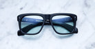 Jacques Marie Mage Yves black rectangular eyeglasses with blue-tinted lenses, shown from above.