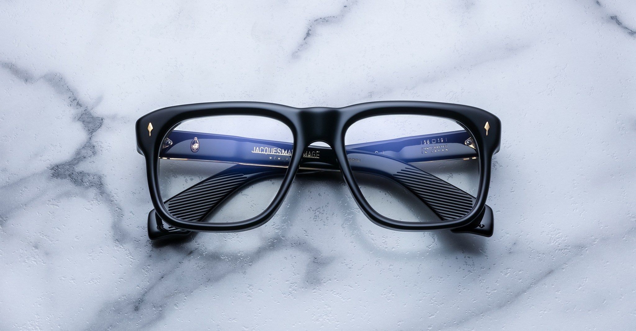 Jacques Marie Mage Yves black rectangular eyeglasses with blue temples, top view.