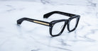 Jacques Marie Mage Yves black rectangular eyeglasses with gold temple detailing, top view.