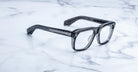 Jacques Marie Mage Yves translucent gray rectangular eyeglasses, top view, displayed on a surface.