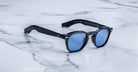 Jacques Marie Mage Zephirin 47 sunglasses with blue lenses shown from above on a flat surface.