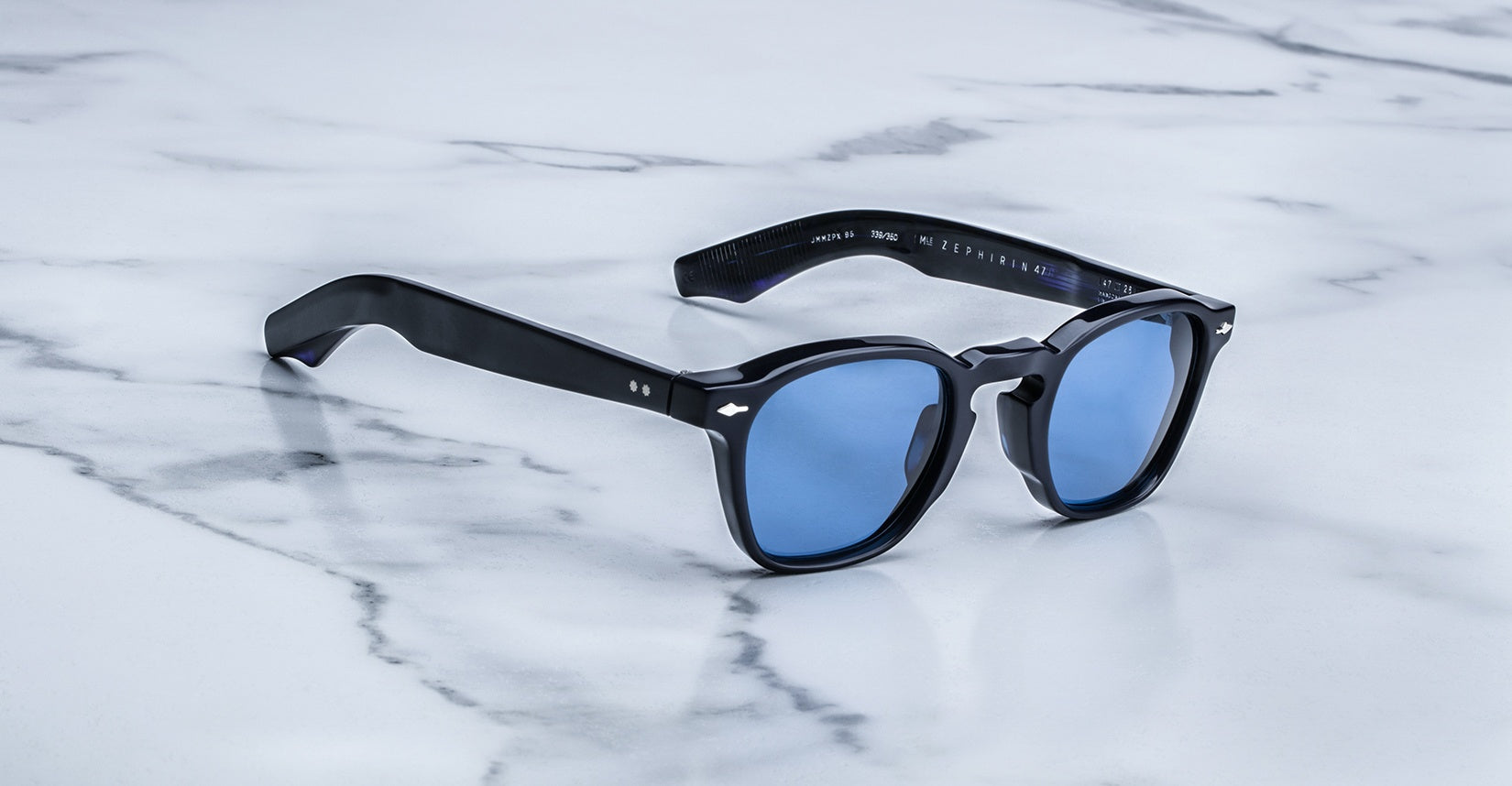Jacques Marie Mage Zephirin 47 sunglasses with blue lenses shown from above on a flat surface.