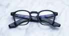 Jacques Marie Mage Zephirin black rectangular eyeglass frames with textured arms are shown closed, face up on marble, highlighting the interior logos—limited edition eyewear handcrafted from premium acetate.