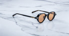 Jacques Marie Mage The Clark round sunglasses with black frames and brown lenses, shown from the front.