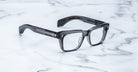 Jacques Marie Mage Molino eyeglasses, thick-rimmed and square with dark translucent frames, shown from above.