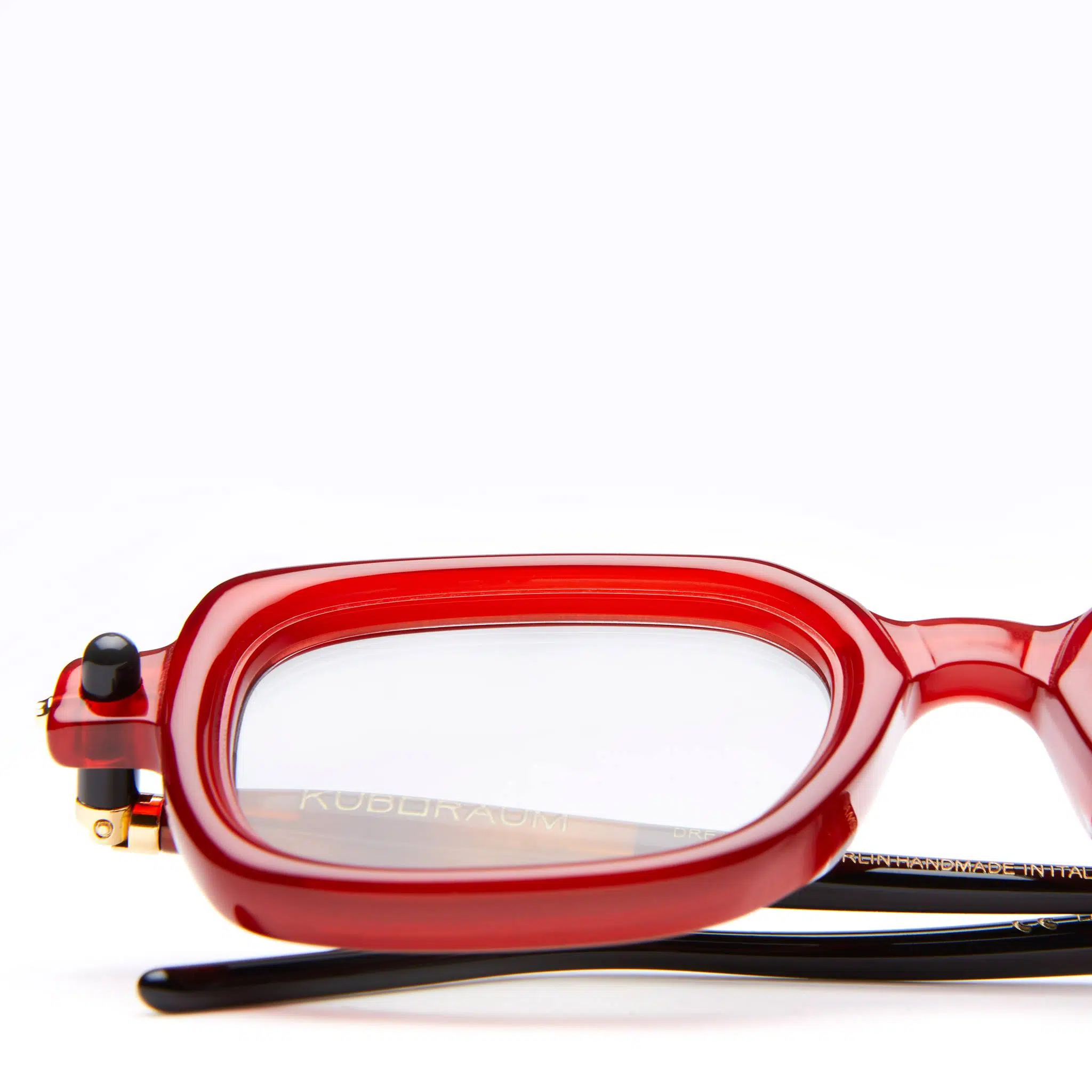Close-up of Kuboraum P4 RED rectangular eyeglasses with clear lenses, showing the left side of the frame and part of the black temple arm, set against a plain white background.