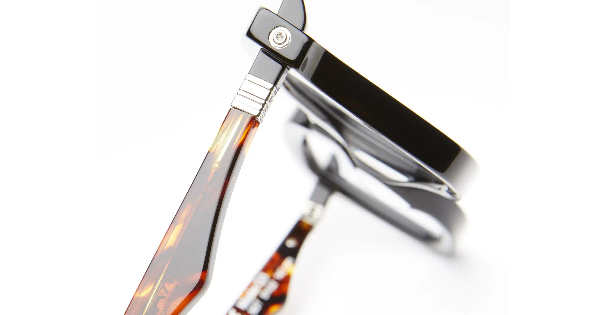 Kuboraum-Q3-BST-Black-Shine-KRO0Q3BST00000OP-Detail2-Dan-Deutsch Close-up view of Kuboraum Q3 eyeglasses with black frames and tortoiseshell-patterned arms, displayed from an angled perspective on a white background.