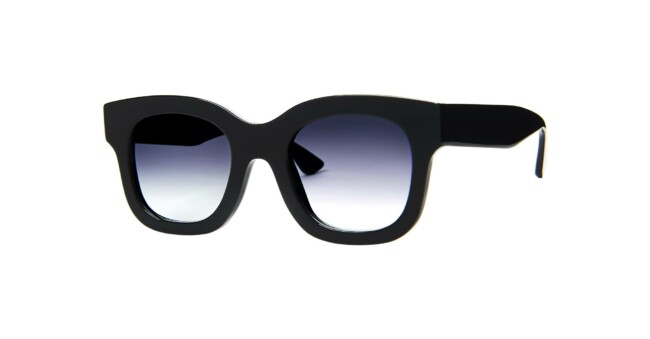 The Thierry Lasry Unicorny features black, thick frames with square lenses and a dark gradient tint, displayed on a white background.