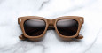 The Jacques Marie Mage Dealan X Umit Benan brown square-framed sunglasses with dark lenses are displayed on a white marble surface.