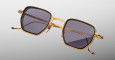The Jacques Marie Mage Atkins sunglasses, featuring square gold metal frames with dark lenses, are displayed against a plain light gray background. The temples include gold detailing and striking red-tipped ends.