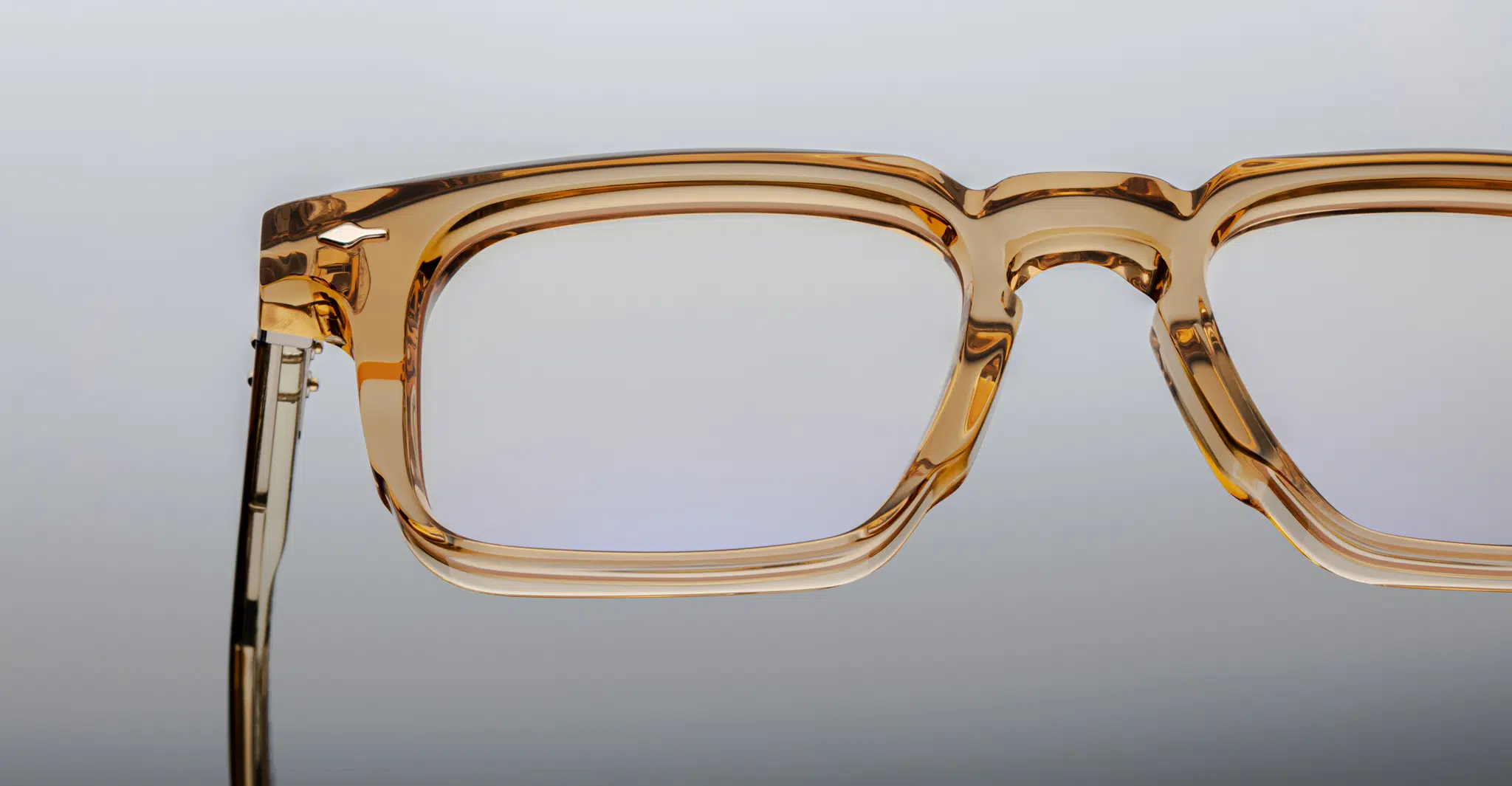 Close-up of the upper half of Jacques Marie Mage Moscova transparent brown rectangular eyeglasses set against a neutral gradient background.
