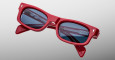 A pair of Jacques Marie Mage Initials red rectangular sunglasses with dark tinted lenses floats against a light gray background. The open arms reveal metallic detailing on the inside.