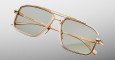 The Jacques Marie Mage Earl sunglasses feature a gold metal frame with rectangular green-tinted lenses, shown at an angle on a light gray background. The double bridge design and engraved branding on the arms complete the look.