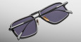 The Jacques Marie Mage Earl is a pair of rectangular sunglasses with black frames, dark lenses, gold-colored nose pads, and extended arms, shown from the back against a plain light background.