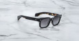 The Jacques Marie Mage Molino 55 black rectangular sunglasses with dark lenses rest on a white marble surface with gray veining.