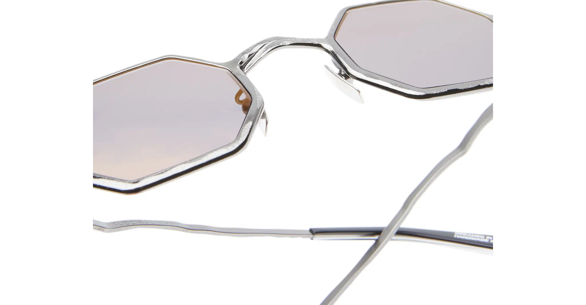 Kuboraum-Z19-GMG-Gun-Metal-KRSZ19GMG00000GF-Detail3-Dan-Deutsch Close-up of Kuboraum Z19 sunglasses, featuring angular silver frames, light pink lenses, and slender metal arms. The image emphasizes the unique geometric design of these standout shades.