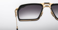 Close-up of the right half of Jacques Marie Mage GT-R sunglasses featuring a black and gold frame and gradient dark lenses, set against a plain white background.