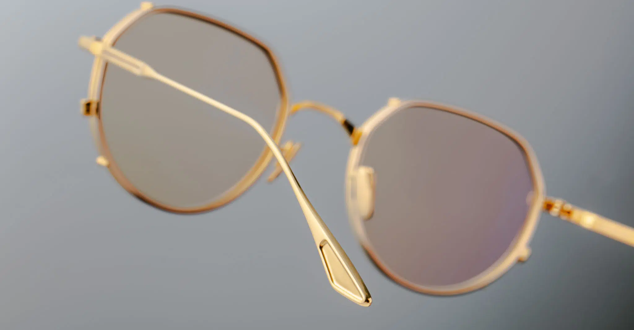 Jacques Marie Mage Hartana in Dorset JMMTN-12Q Close-up of Jacques Marie Mage Hartana eyeglasses featuring a gold geometric frame and light-tinted lenses, showcased at an angle that accentuates the thin metal construction against a softly blurred background.