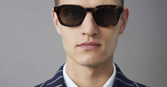 Model with slicked hair and striped suit wearing Thom Browne 412 Sunglasses in Honey Tortoise